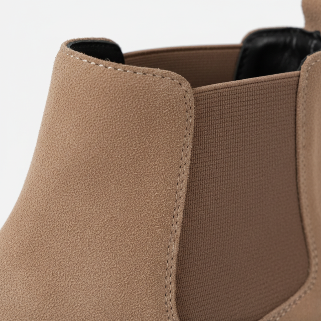 Close-up of men's beige suede Chelsea boots showing elastic side panel and premium construction detail