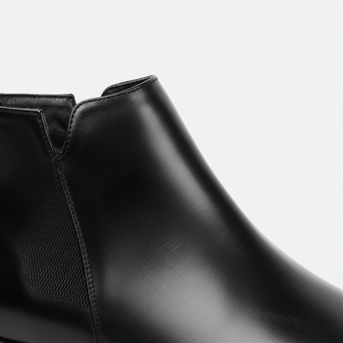 Close-up detail of men's black leather Chelsea boots showing elastic gusset and premium construction quality