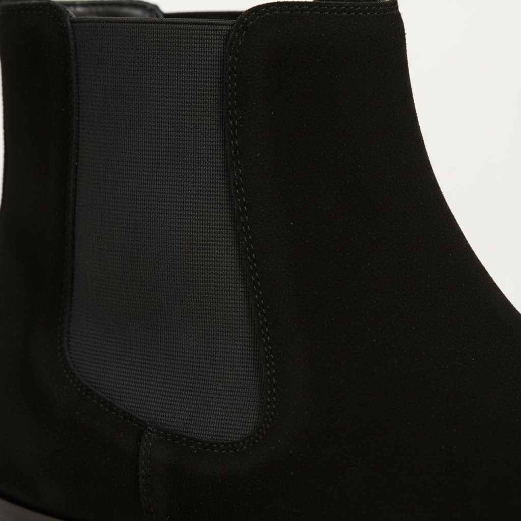 Close-up of men's black suede Chelsea boots showing elastic side panel and premium construction detail