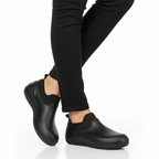 Black waterproof slip-on work shoes with anti-slip rubber sole styled with black trousers - Lewis Fordham UK