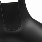 Close-up detail of black Chelsea boot showing brown elastic panel and tan contrast stitching