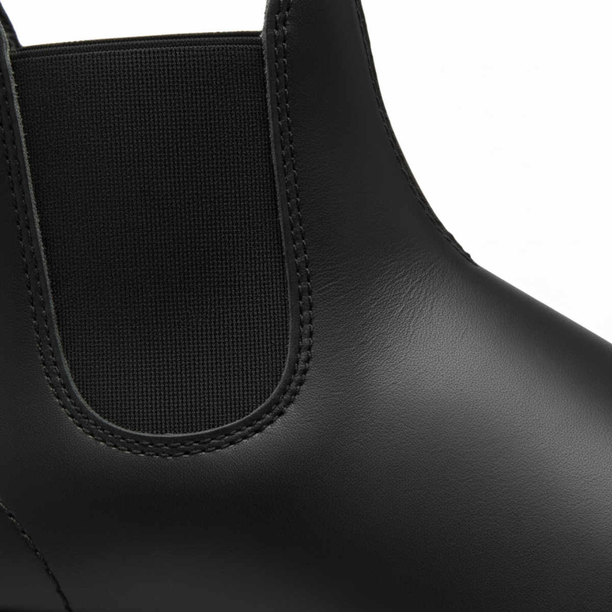 Close-up detail of black Chelsea boot showing brown elastic panel and tan contrast stitching