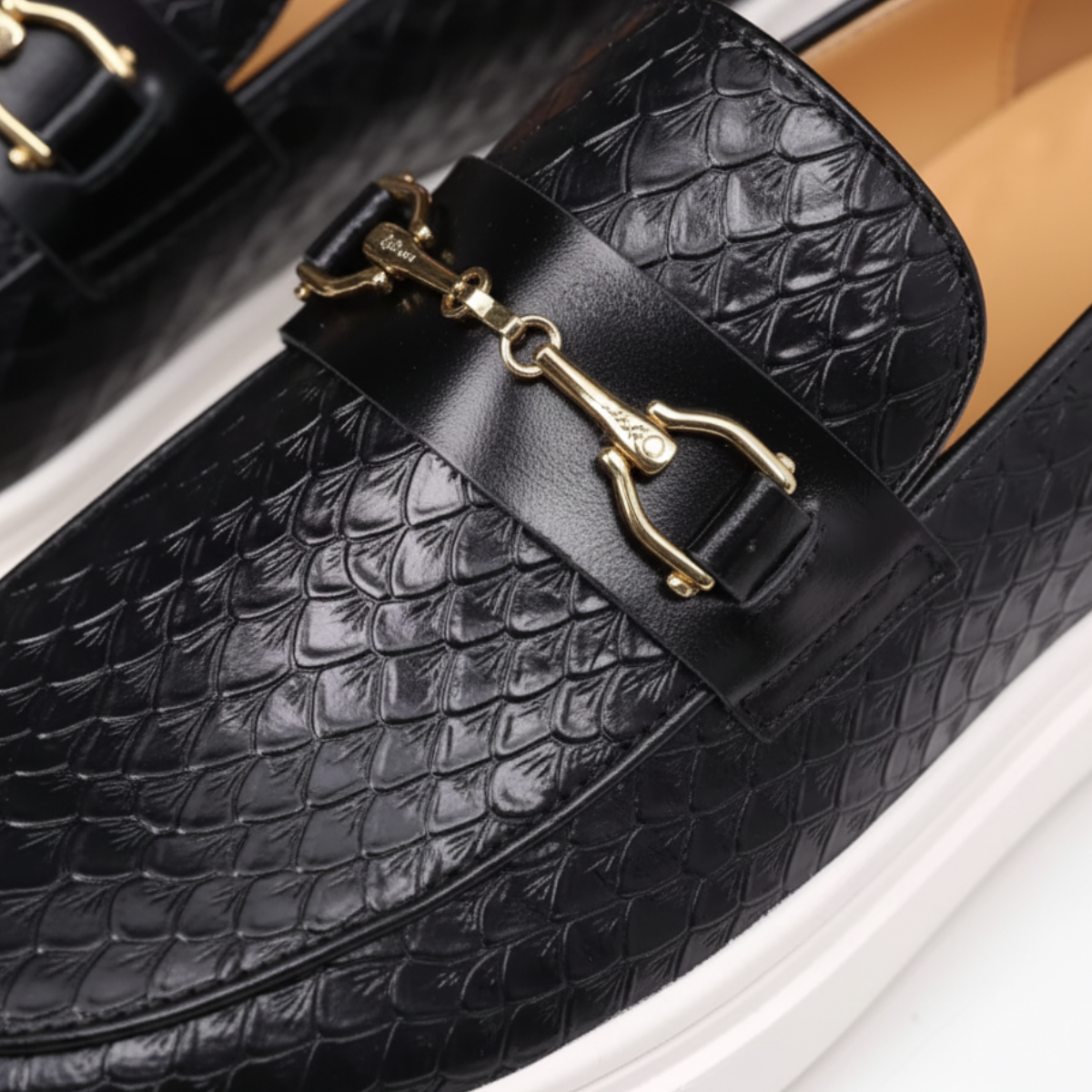 Close-up detail of black crocodile embossed loafer showing gold horsebit hardware and textured leather pattern