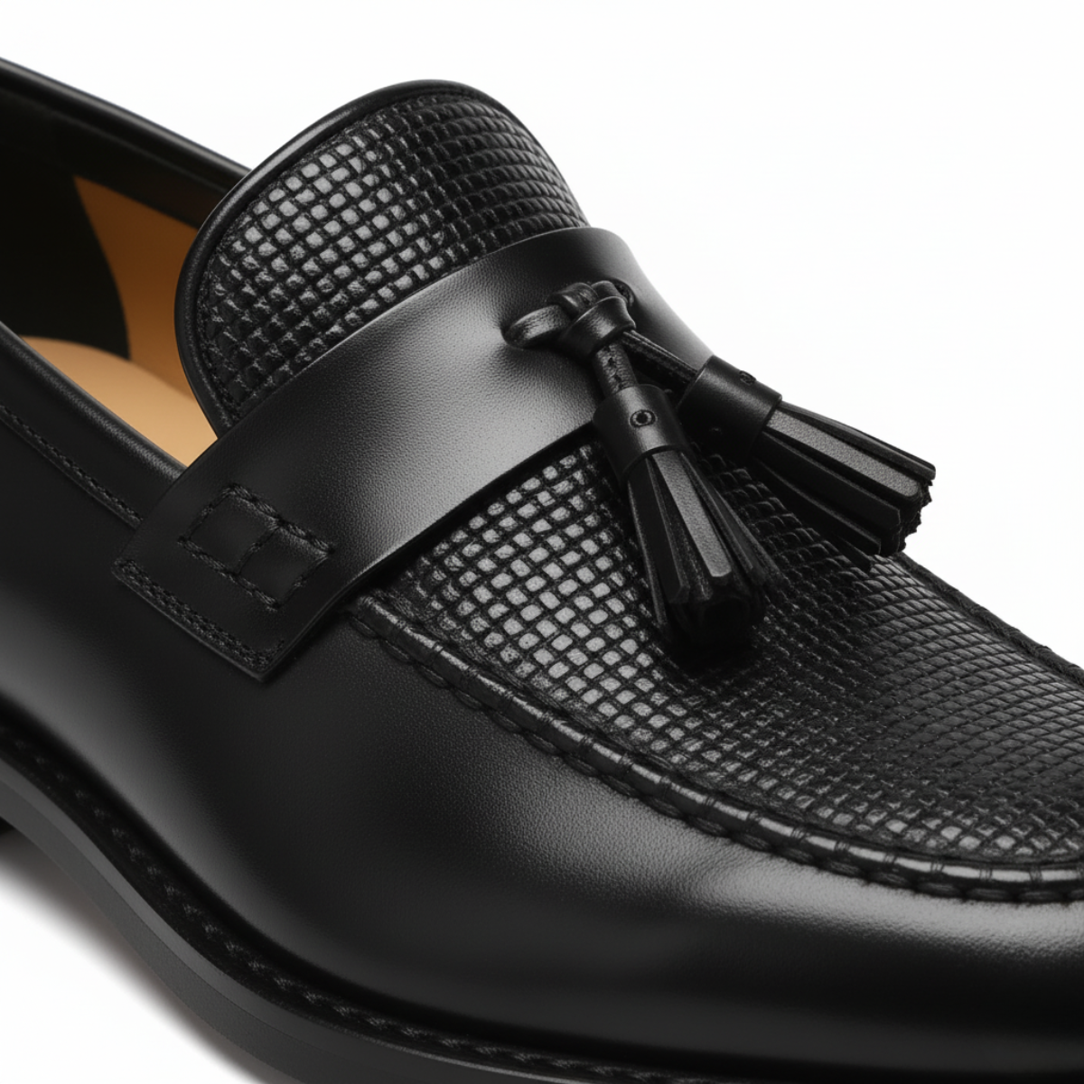 Close-up detail of black leather tassel loafer showing basket weave texture and decorative tassel accent