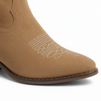 Close-up of tan Western boot showing white contrast embroidery and suede pointed toe