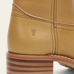Close-up detail of tan leather knee-high boots showing contrast stitching and stacked block heel