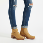 Tan leather knee-high boots for women styled with rolled denim jeans showing ankle fit